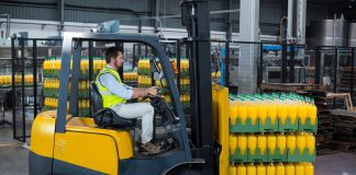 Factory worker loading packed juice bottles on forklift