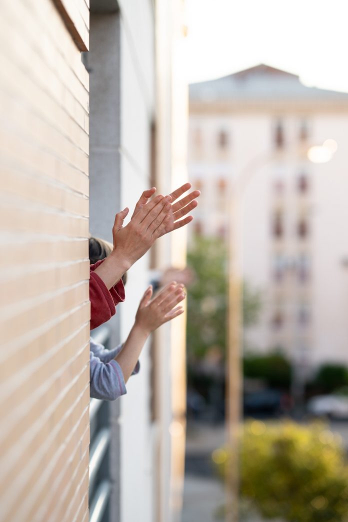 People clapping in the window in support of people who fight against the coronavirus